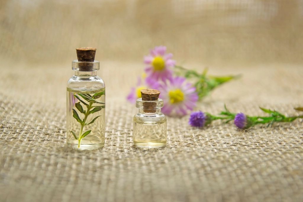 Due boccette di olio essenziale accanto a fiori di campo