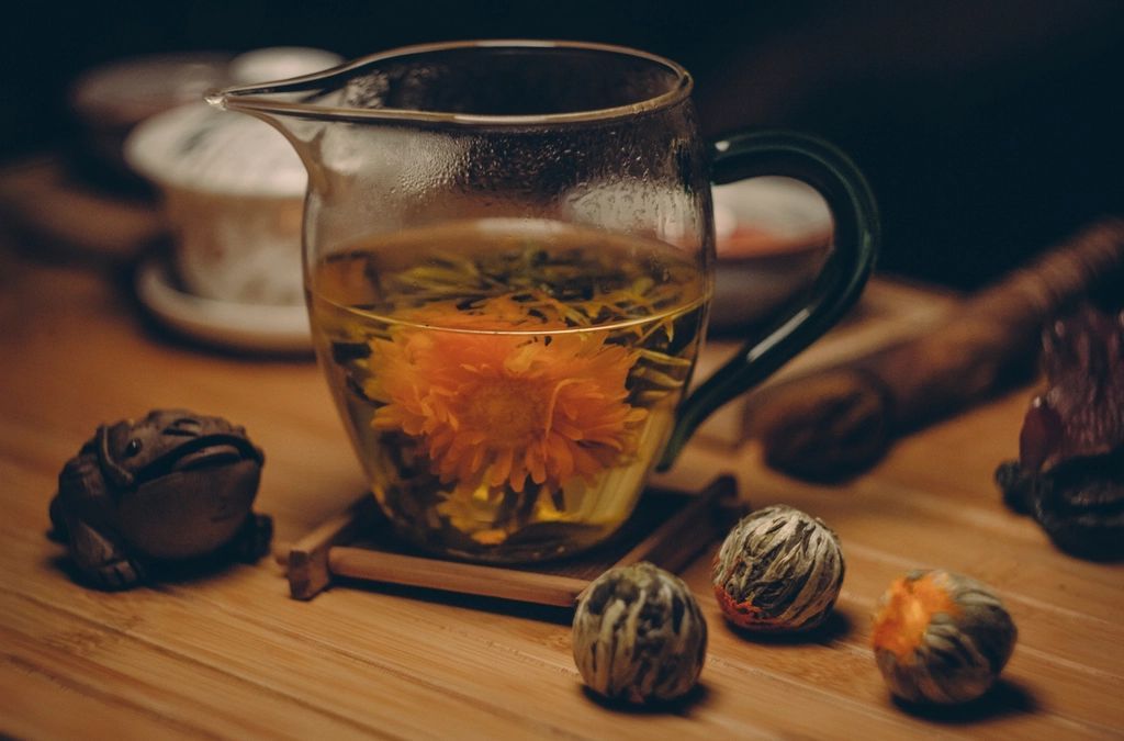 Teiera di vetro con un infuso di fiori, luce calda
